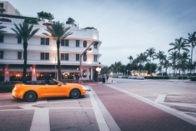 Auto muscle car amarillo convertible girando a Ocean drive en miami beach al atardecer